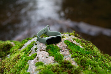 fitness tracker on a stone cover with moss near a river