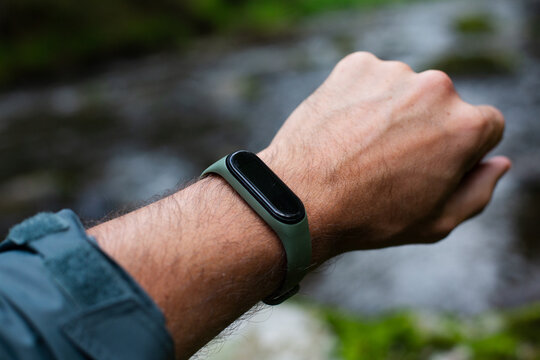 fitness tracker on a man's hand in the forest near river