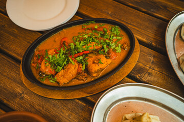 Enjoy the art of dining as chicken chakhokhbili is served with vibrant herbs and spices in a rustic atmosphere Experience the rich taste and cultural essence