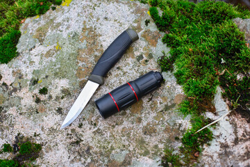 camping knife and monocular on a stone near a river