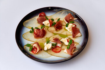 Elegant Plate of Gourmet Appetizers Featuring Thinly Sliced Pears, Prosciutto, Goat Cheese, and...