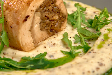 Deliciously Prepared Rolled Chicken Breast with Herb Filling on a Creamy Garlic Sauce Base Surrounded by Freshly Chopped Greens and Drizzled with Olive Oil