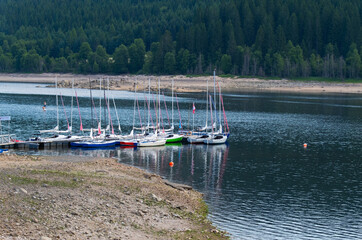 yachts near pier on the tranquil lake with forest coast
