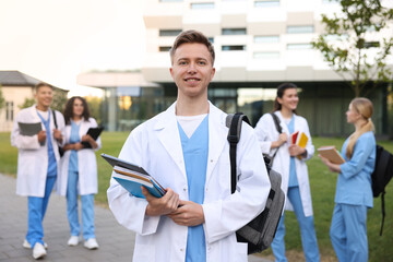 Obraz premium Medical student in uniform with backpack, laptop and notebooks outdoors, selective focus