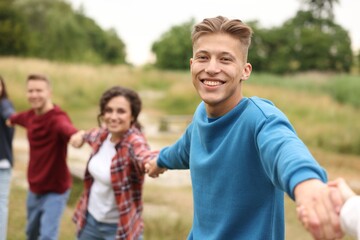 Team building. Group of happy people holding hands outdoors, selective focus