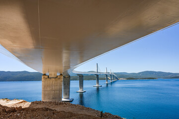 Modern architectural view of Peljesac Bridge in Croatia captured from below with clear blue sky and...