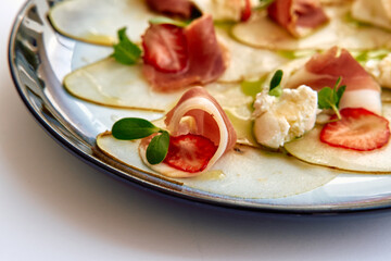A Culinary Delight Featuring Delicate Prosciutto Rolled with Fresh Strawberries and Soft Cheese on a Fine Plate for an Inviting Gourmet Experience