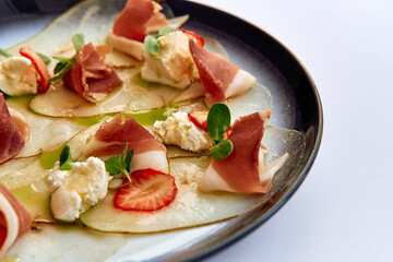 Delicately Crafted Dish Featuring Thinly Sliced Meat, Fresh Cheese, and Complementary Fruits Drizzled with Olive Oil, Perfect for Gourmet Dining Experiences