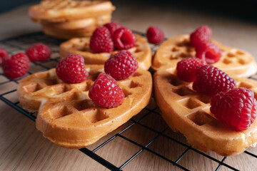 Heart-shaped waffles with fresh raspberries on a cooling rack