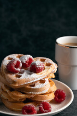 Stack of heart waffles with raspberries and coffee