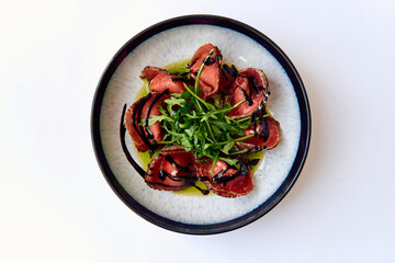 An Elegant Presentation of Tender Beef Slices Drizzled with Balsamic Reduction and Garnished with...