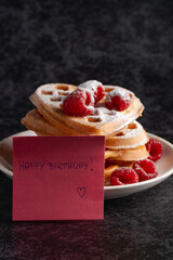Heart-shaped waffles with birthday note and berries