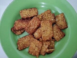 close up of a pile of fried tempeh on a green plate