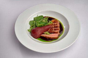 A Gourmet Meal Featuring Tenderly Cooked Duck Breast Served with Fresh Greens and a Juicy Poached Pear in a Delicious Sauce