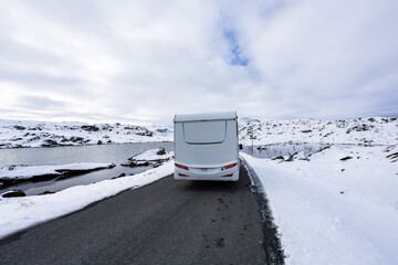 A motorhome driving along the Sognefjellsvegen road in Norway, surrounded by snow-covered mountains...