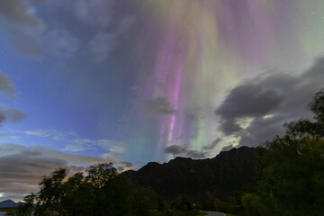 The stunning Northern Lights over Lofoten Islands, Norway, with vivid colors lighting up the night sky above mountains.