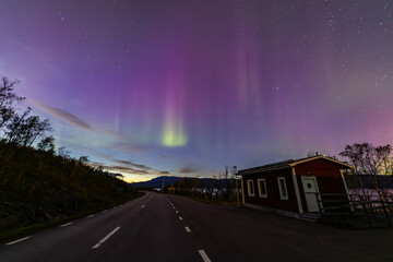 Northern lights in Kiruna, Sweden, reflecting on calm water in September with stars and forest in...