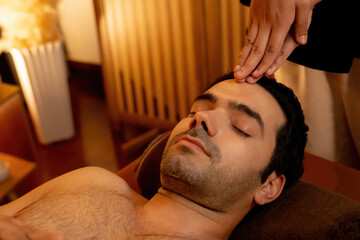 Caucasian man enjoying relaxing anti-stress head massage and pampering facial beauty skin...