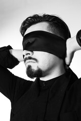 A man with his eyes blindfolded. Studio photo