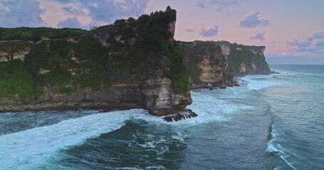 Aerial drone footage captures the breathtaking Uluwatu Temple perched atop a majestic cliff as...