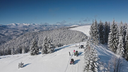 Aerial drone footage tourists riding snowmobiles and taking pictures in a snowy mountain forest,...