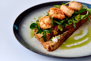 Delicious Shrimp Toast with Fresh Greens and a Drizzle of Olive Oil on a Stylish Black Plate