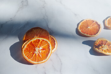 Dried oranges are placed on a white marble table.