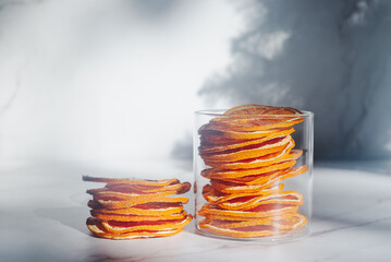 dried orange slices in a glass container on white marble table.