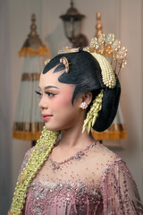 An elegant Asian bride in traditional Javanese kebaya, gracefully posing sideways with floral hair...