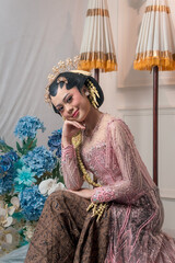 Charming Asian bride in a pink beaded kebaya with jasmine hairpiece and traditional Javanese style,...