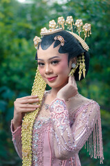 Portrait of a beautiful Indonesian woman in traditional bridal kebaya and intricate jasmine...