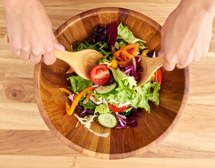 Preparing a Vibrant Salad: A person is carefully mixing a fresh, colorful salad in a wooden bowl, showcasing healthy eating and culinary artistry.
