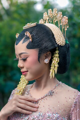 Close-up of a beautiful Asian bride wearing traditional Javanese hair accessories, jasmine garland,...