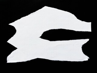 A torn white sheet of paper isolated on a black background. White paper looks antique with torn and...