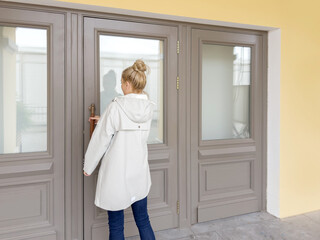 Woman opening doors of house (hotel, store)