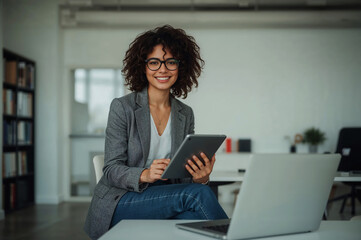 Empowered woman smiles navigating digital work on a tablet in a bright office with casual