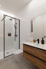 Modern bathroom with a glass shower, wooden vanity, and minimalist decor. Neutral colors create a clean and spacious atmosphere.