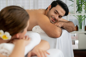 Blissful couple customer having exfoliation treatment in luxury spa salon with warmth candle light...