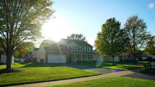 Suburban colonial-style house on a sunny day with bright green lawn and large trees