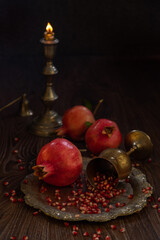 Pomegranates, silver wine goblet and burning candle on wooden table – concept  Rosh Hashanah.