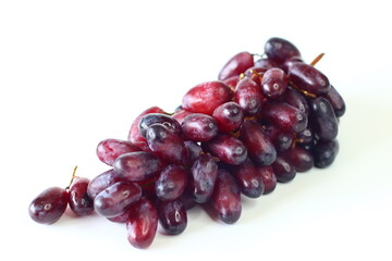 Fresh black seedless grapes, oval and elongated variety, arranged on a white background