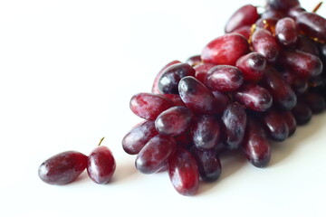Fresh black seedless grapes, oval and elongated variety, arranged on a white background