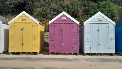 Colourful summer beach huts lined up on the seashore in England