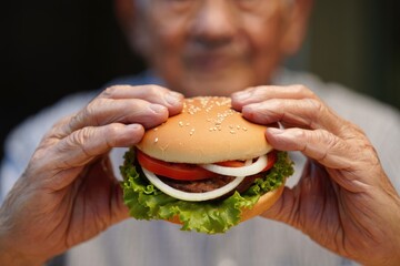 An elderly man holds a tasty burger, showcasing the ingredients and fresh food.