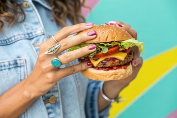 Woman holding a tempting burger ready to be enjoyed with fresh ingredients.