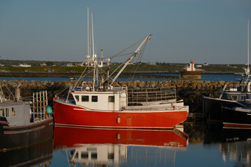 Colorful red fishing trawler with a perfect reflection at sunset in Yarmouth Harbor Nova scotia...