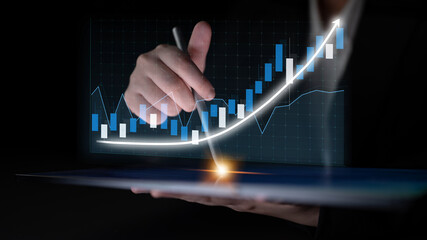 A business professional reviews financial data using a tablet, highlighting growth trends with a...