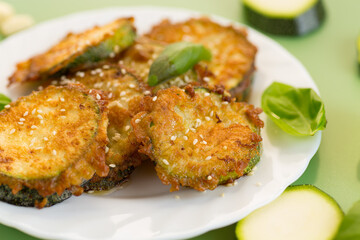 Fried zucchini pieces under sesame seeds and fresh basil