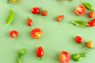 Cherry tomatoes and basil leaves on soft green background