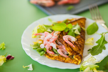 Appetizing breakfast omelette with shrimps and dill, on a green background